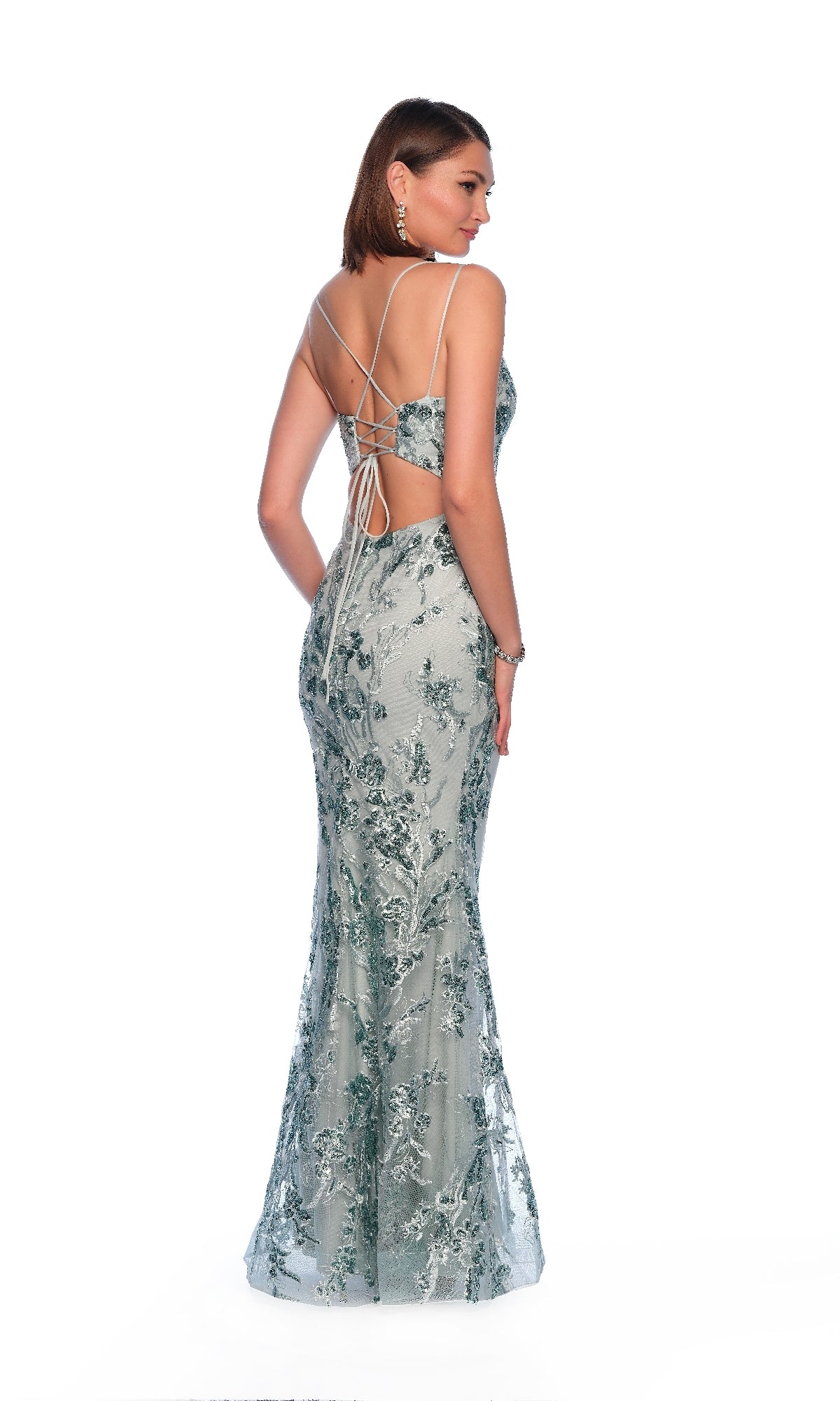 Woman wears the Dave and Johnny 12089 long prom dress with silver sequin-lace floral embroidery and a crisscross open back, standing against a white background.